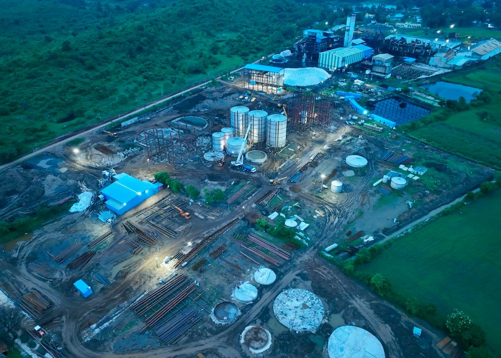 The distillery site at dusk, storage tanks lit against the sky